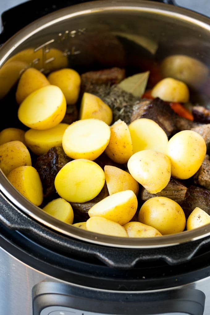 Receta de estofado de carne instantánea | Estofado de ternera en olla a presión | Estofado de ternera #beef #stew #soup #pressurecooker #instantpot #dinner #dinneratthezoo Carne, verduras y patatas nuevas cortadas por la mitad en una olla a presión.