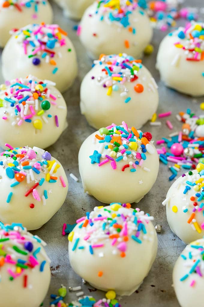 Receta de la bola de pastel | Pastel de trufa | Bocaditos de pastel # pastel # postre # postres #dinneratthezoo Bolas de bizcocho cubiertas con chocolate blanco y espolvoreadas en una bandeja para hornear.
