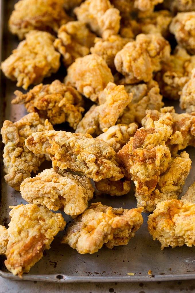 Trozos de pierna de pollo frito en una bandeja para hornear.