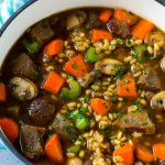 Una olla llena de sopa de cebada de ternera hecha con estofado de ternera, cebada y verduras hervidas juntas.