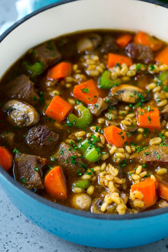 Una olla de sopa de cebada con setas, zanahorias y apio.