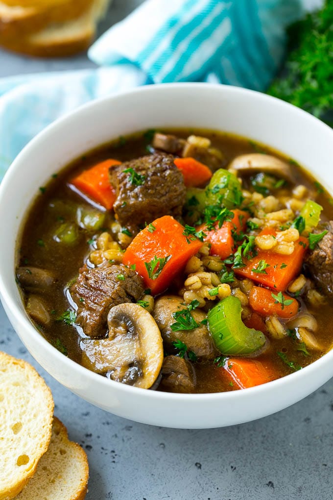 Un tazón de sopa de cebada de res con guarnición de perejil picado.