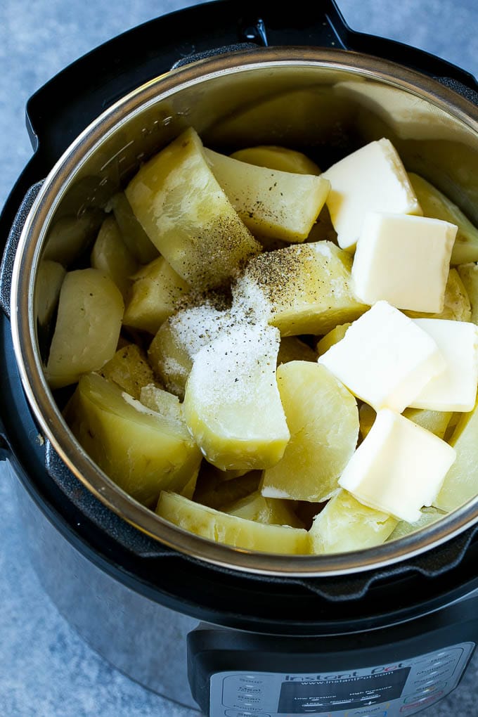 Trozos de patata cocidos con mantequilla, leche y condimentos en una sartén instantánea.