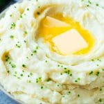 Un tazón de puré de papas instantáneo cubierto con trozos de mantequilla y cebollino en rodajas.