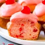 Muffins de cereza espolvoreados con cerezas al marrasquino y cubiertos con glaseado rosa.