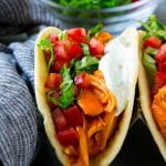 Tacos de pollo búfalo con pollo picante, tomates cortados en cubitos, lechuga rallada y salsa ranch.