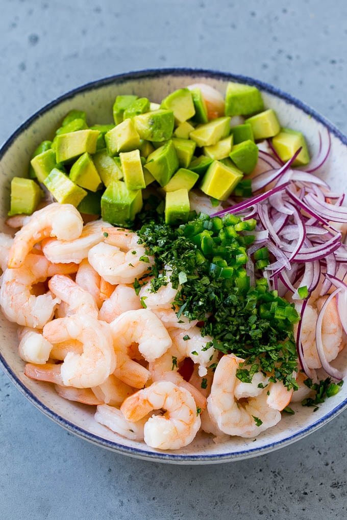 Camarones, cebolla morada, aguacate, jalapeño y cilantro en un tazón para servir.