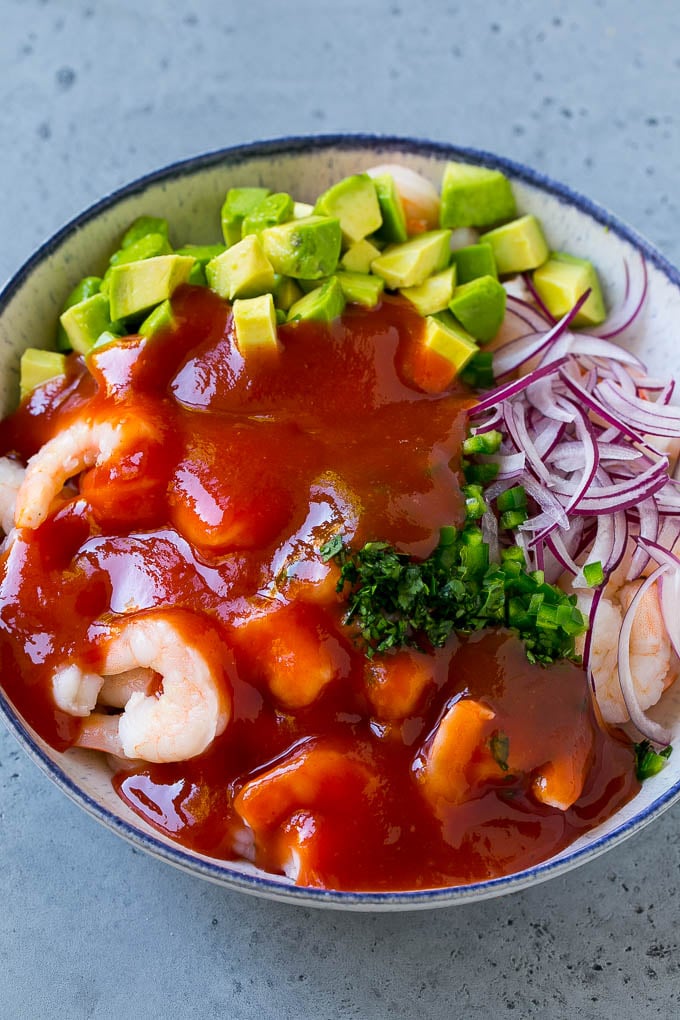 Camarones, aguacate, cebolla morada y cilantro cubiertos con salsa coctel.