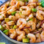Un tazón para servir de cóctel de camarones mexicano que contiene camarones, aguacate cortado en cubitos, hierbas y jalapeño.
