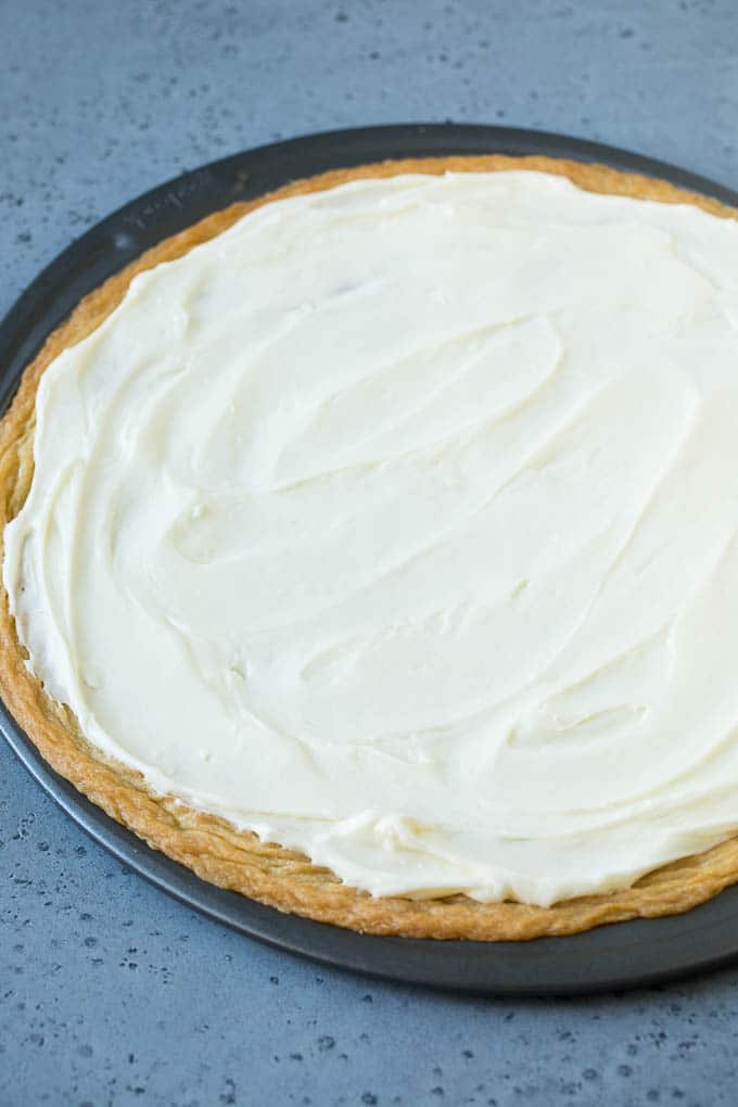 Una corteza de galleta de azúcar cubierta con una capa de glaseado de queso crema.