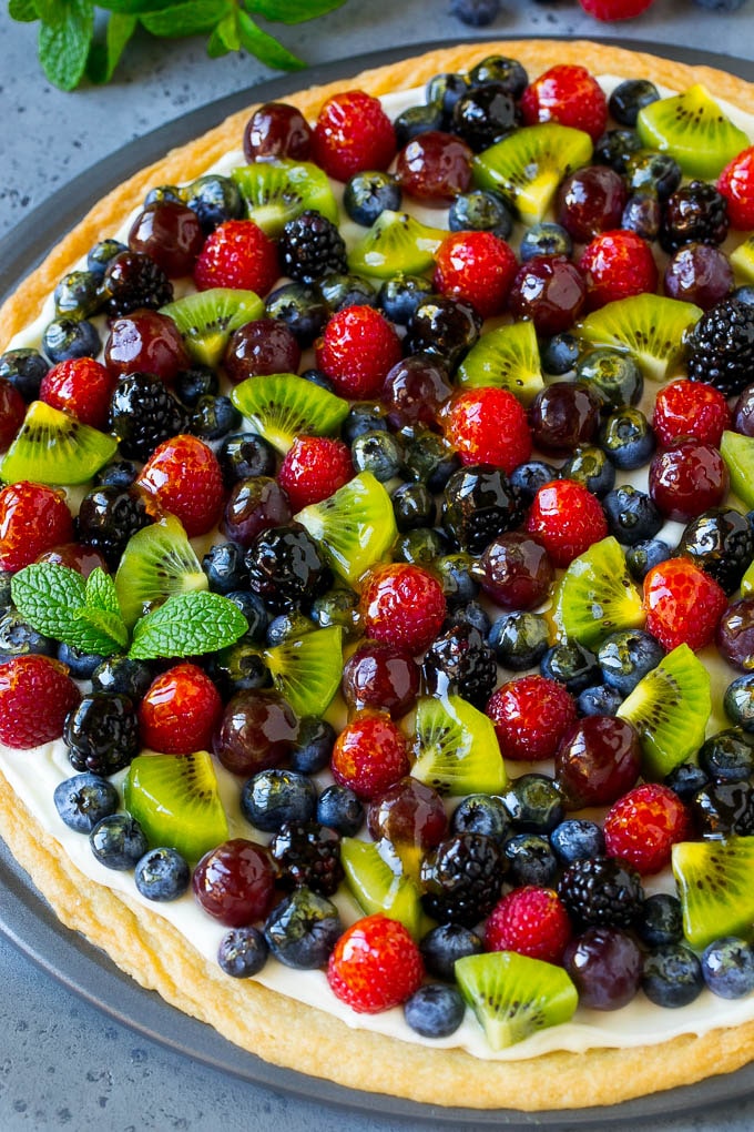 Una pizza de frutas cubierta con bayas, kiwi y uvas.