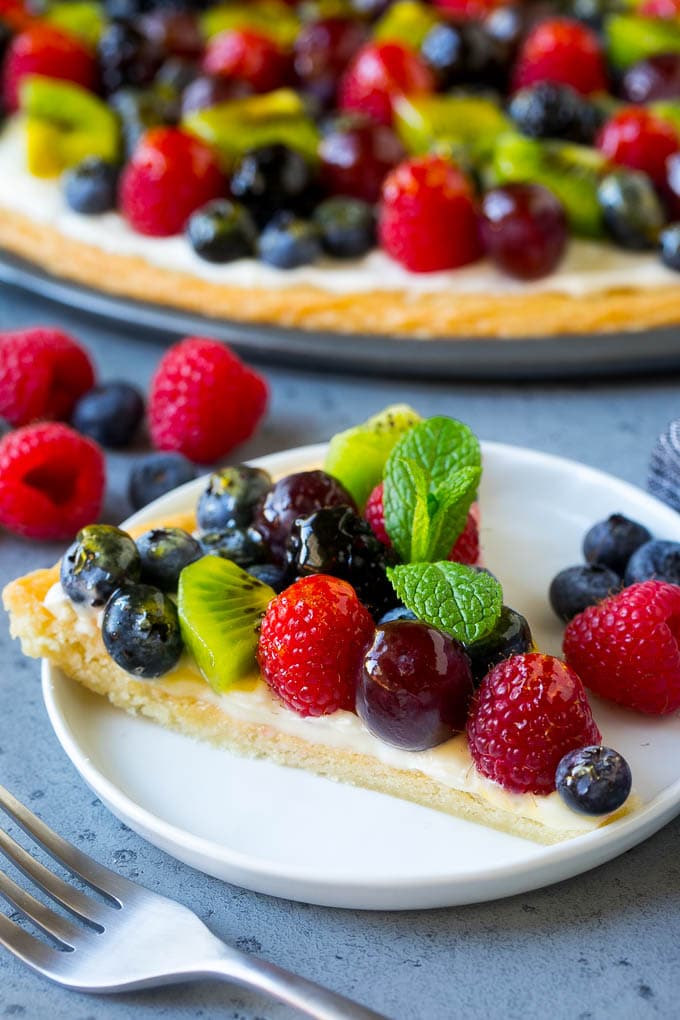 Una rebanada de pizza de frutas cubierta con glaseado de queso crema y bayas.