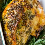 Pechuga de pavo asada con ajo y hierbas en una fuente para asar con guarnición de romero.