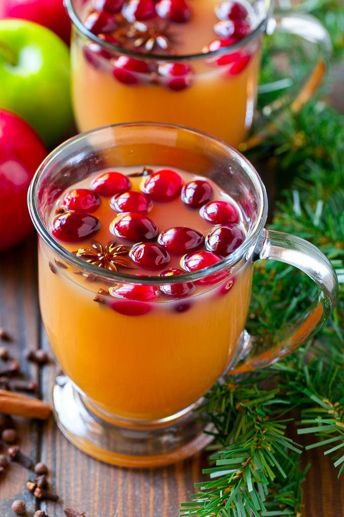 Vasos de sidra de manzana cocidos a fuego lento cubiertos con arándanos.