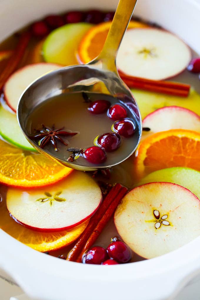 Un cucharón que recoge la sidra de manzana en la olla de cocción lenta.