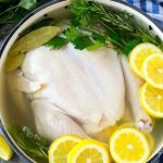 Ponga el pollo en salmuera en una cacerola con pollo entero, limones, hierbas y especias.