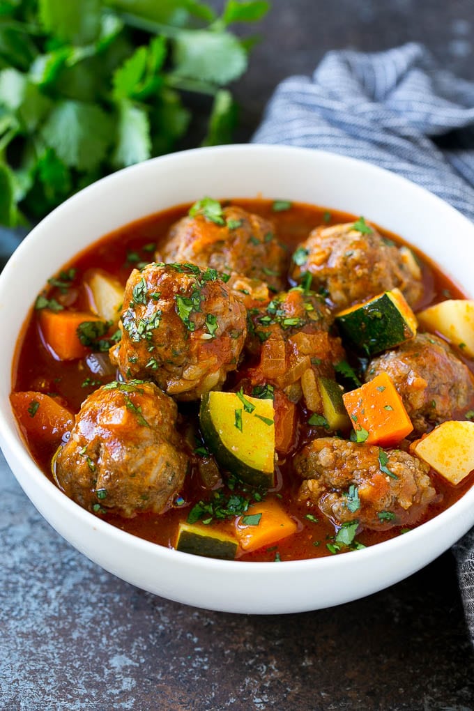 Un plato de sopa de albóndigas con albóndigas, zanahoria, calabacín y tomate.