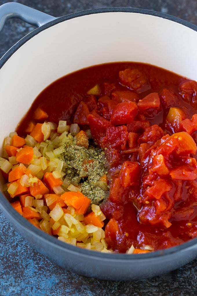 Verduras, tomates y hierbas en una tetera.