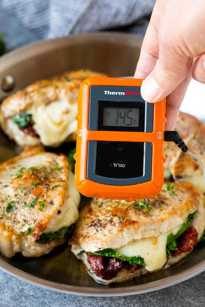 Un termómetro en una chuleta de cerdo rellena que marca 145 grados F.