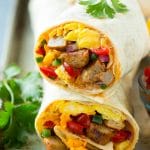 Una sección transversal de un burrito de desayuno relleno con huevos, salchichas, frijoles y queso.