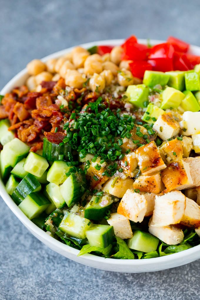 Ingredientes para ensalada de pollo molido en un tazón para servir, cubierto con aderezo de la casa y espolvoreado con cebollino.