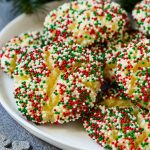 Un plato de galletas de mantequilla pegajosas cubiertas con chispitas navideñas.
