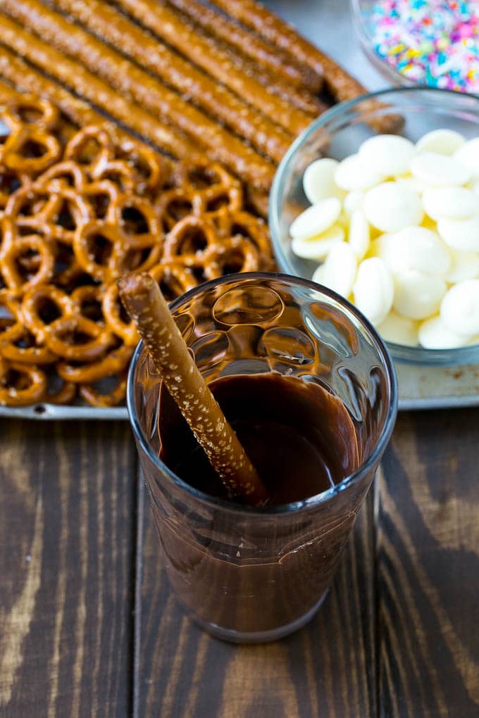 Una baguette de pretzel en un vaso lleno de chocolate derretido.