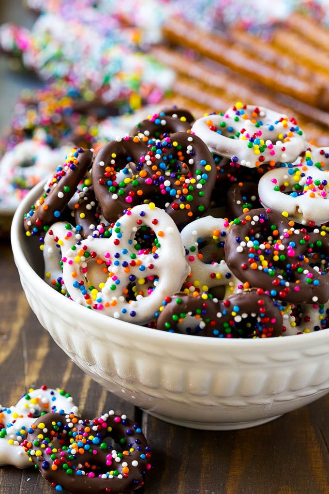 Un tazón de pretzels cubiertos de chocolate decorado con chispitas de arco iris.