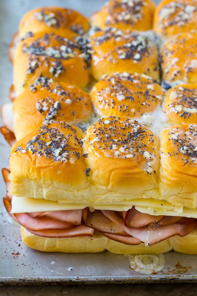 Un paquete de sándwiches enrollados cubiertos con jamón, queso, mantequilla de semillas de amapola y cebolla.