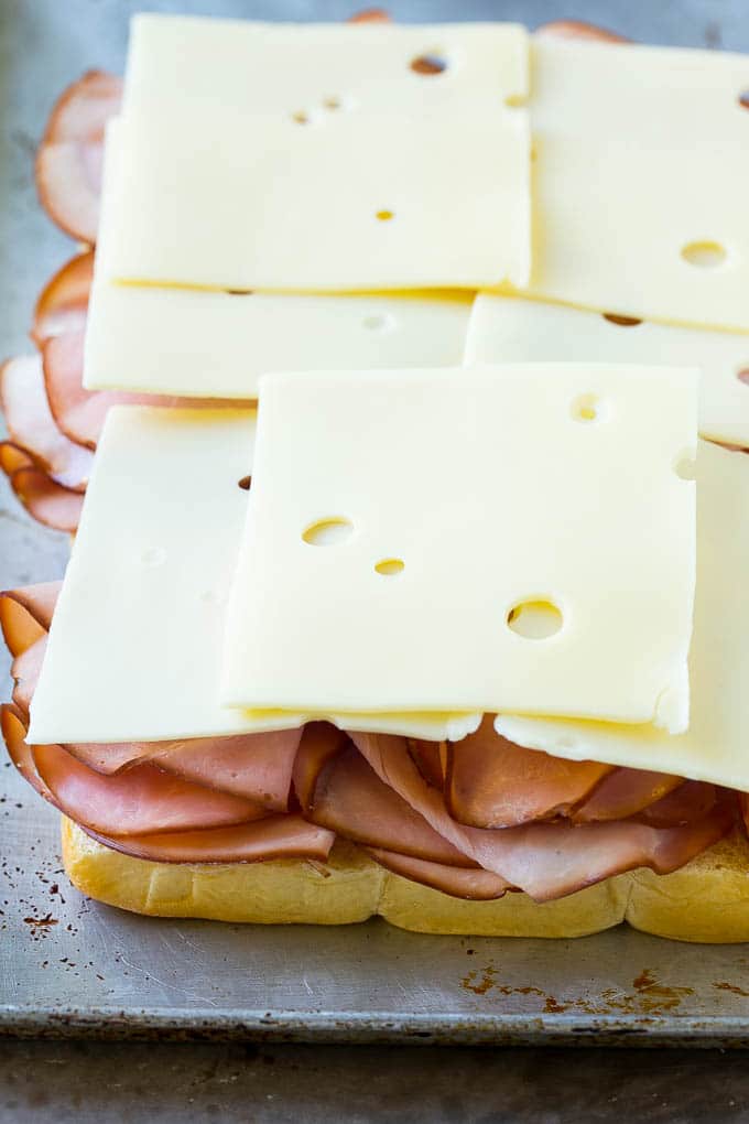 Jamón suizo y queso apilados en bollos hawaianos.