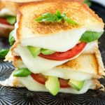 Esta receta de sándwich caprese es la combinación clásica de tomate, mozzarella y albahaca con la bienvenida adición de rodajas de aguacate, todo intercalado entre rodajas de pan tostado con mantequilla.  ArtesanoBread AD