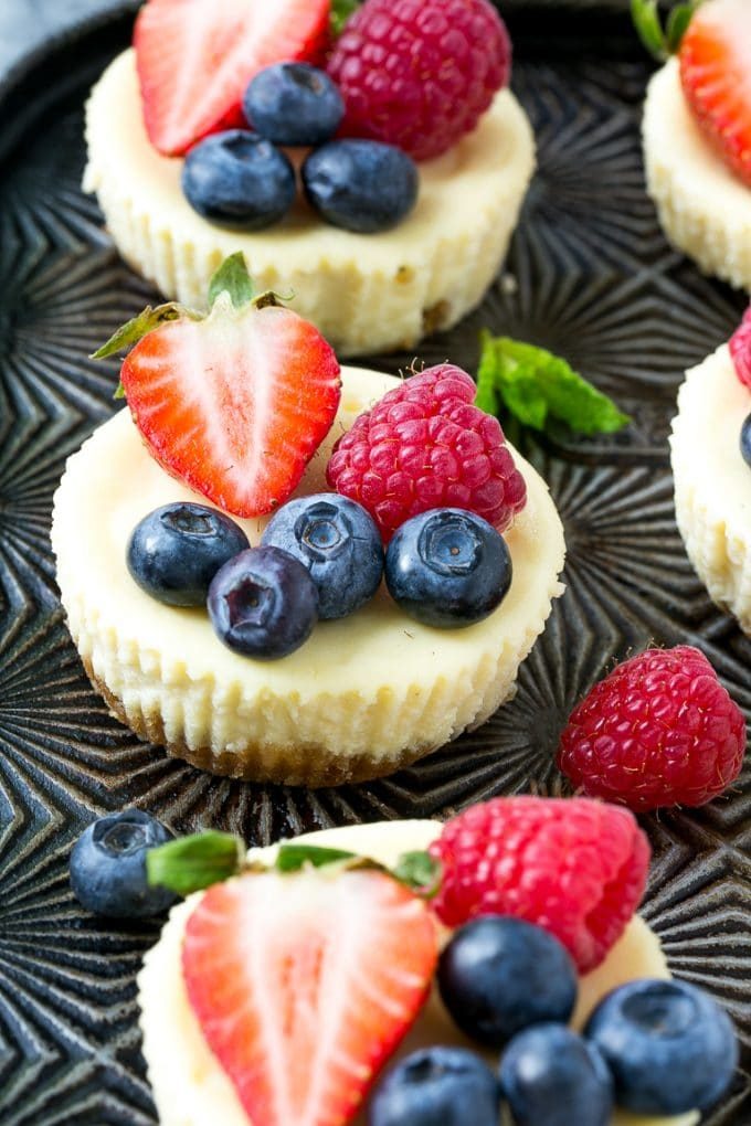 Mini tarta de queso de yogur griego cubierto con fruta fresca y adornado con menta.