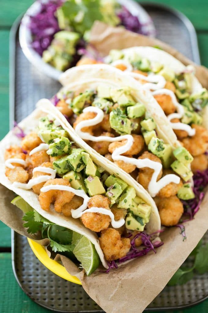 Una canasta de tacos de camarones crujientes con salsa de aguacate.
