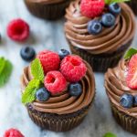 Esta receta de magdalenas de chocolate y avellanas está hecha con magdalenas de chocolate rellenas de chocolate con leche y crema de chocolate con avellanas, luego terminadas con glaseado de chocolate y avellanas y bayas frescas.  ¡El regalo perfecto para una ocasión especial!  #chocmeister #chocolatehazelnut #ad