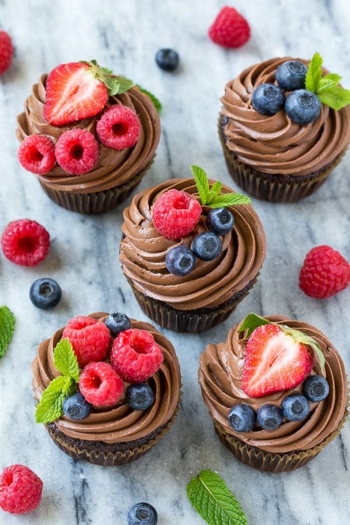 Cupcakes de chocolate y avellanas con guarnición de frutos del bosque y ramitas de menta.