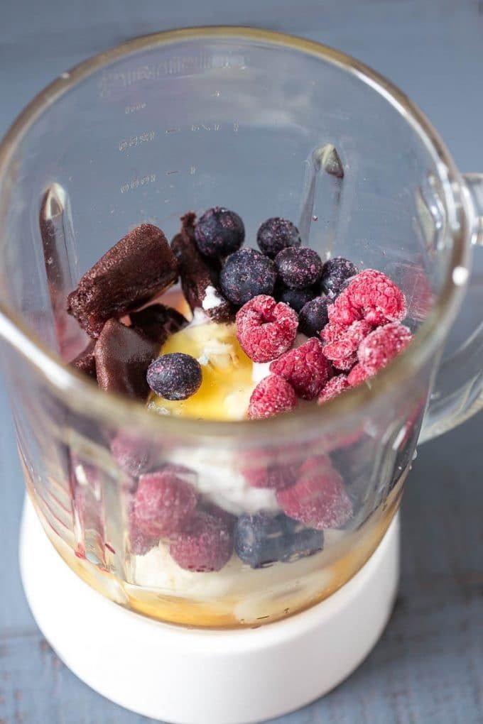 Una licuadora llena de fruta congelada y yogur.