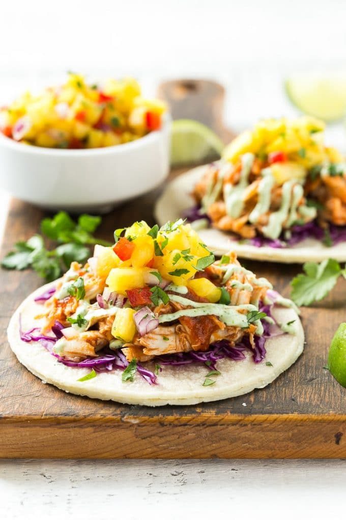 Una tortilla cubierta con repollo, pollo desmenuzado y salsa de piña.