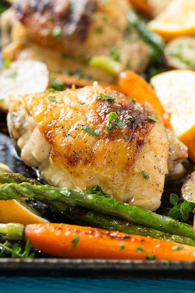 Pollo con limón y tomillo en una bandeja de horno con espárragos y zanahorias.