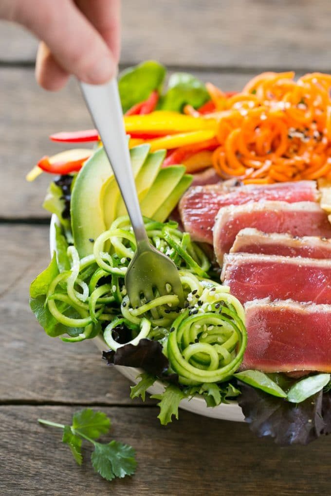 Ensalada de atún ahi chamuscado sobre un lecho de vegetación con pimientos, tiras de wonton y pepino.