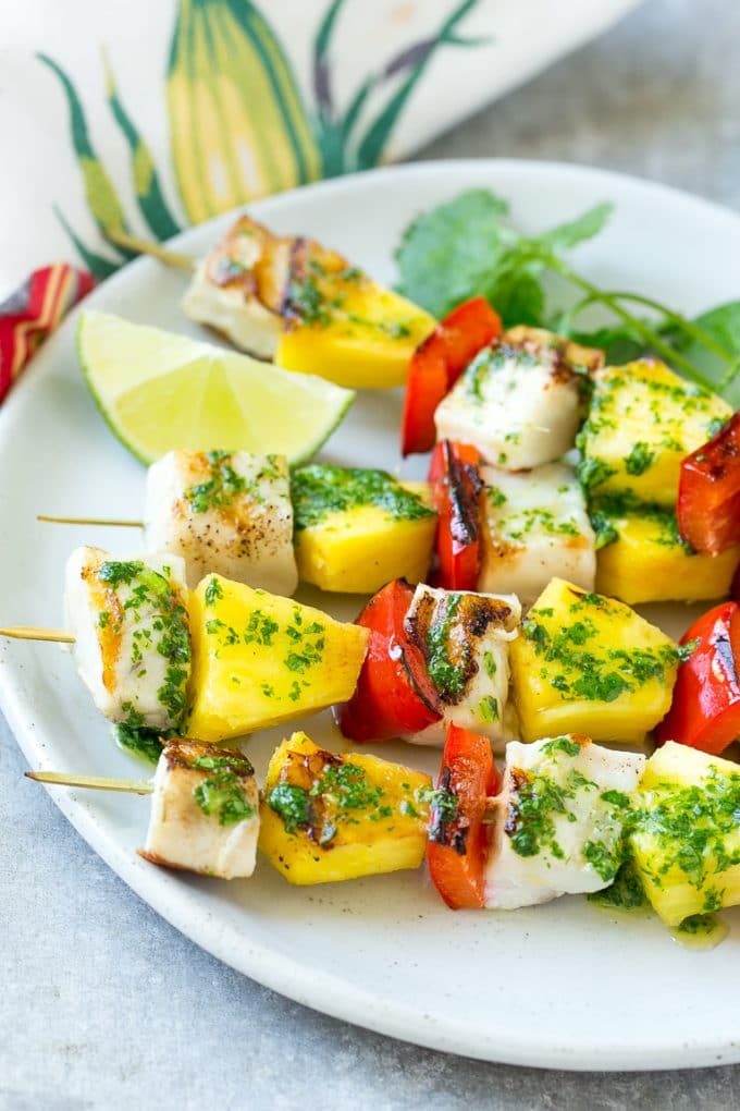 Brochetas de mojo de pescado con rodajas de lima y cilantro para decorar.