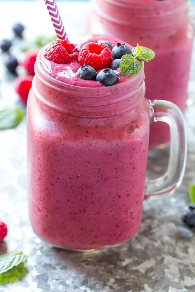 Un vaso de batido de bayas mezclado con frambuesas, arándanos y menta fresca para decorar.