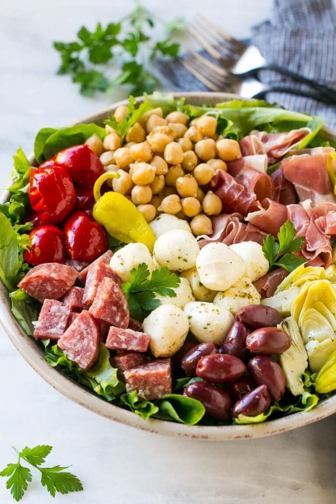 Ensalada de aperitivo con salami, mozzarella fresca y pimientos asados ​​sobre ensalada verde.