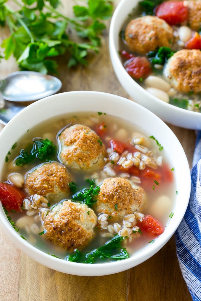 Dos tazones de sopa de espelta con tomates, albóndigas y col rizada.