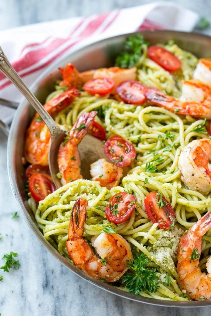 Una cuchara para servir en una olla de pasta al pesto de camarones.
