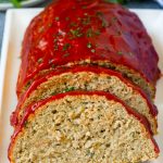 Un pastel de carne de pavo en rodajas cubierto con salsa de tomate y perejil picado.