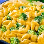 Una sartén de macarrones con queso y brócoli en una cremosa salsa de queso cheddar.