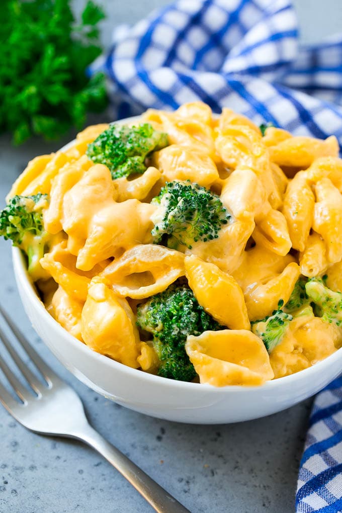 Un tazón de macarrones con queso y brócoli con fideos hervidos, queso cheddar y floretes de brócoli.