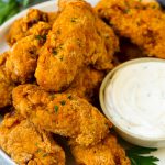 Un plato de alitas de pollo frito servido con salsa ranchera.