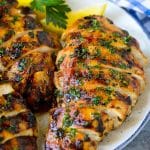 Pechuga de pollo a la plancha en rodajas adornada con hierbas y limón.