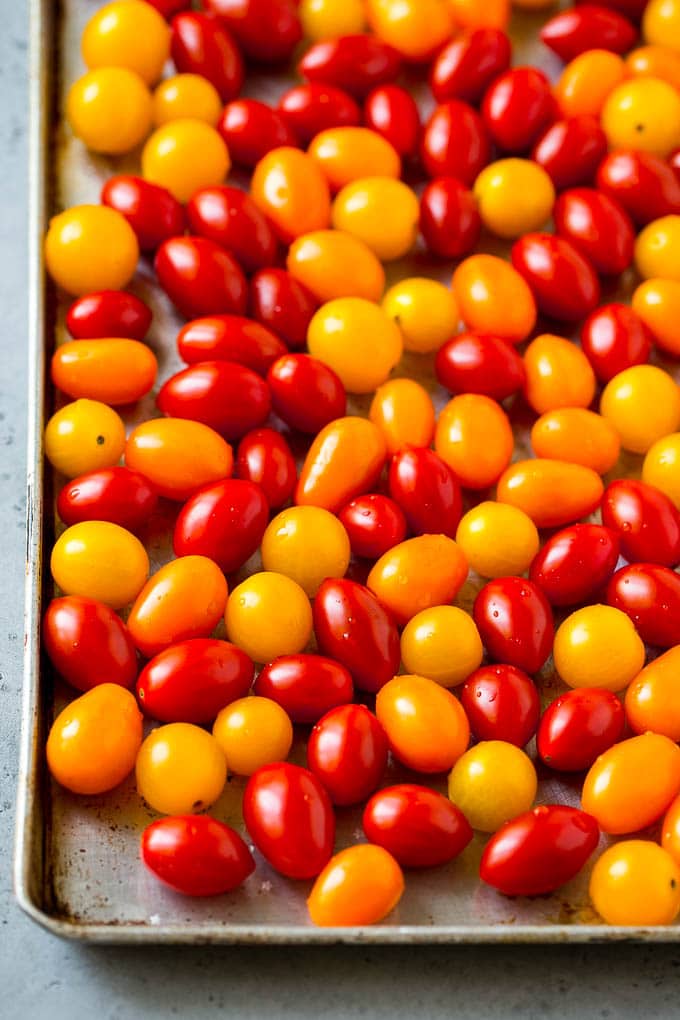 Tomates cherry rojos, naranjas y amarillos en una bandeja para hornear.